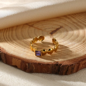Detailed close-up of a gold ring with square purple stone on a wooden base