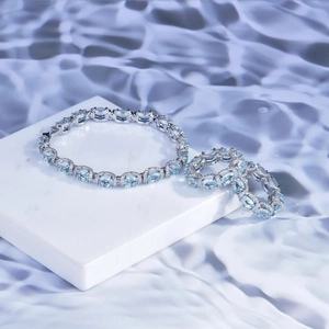 Detailed shot of aquamarine jewelry set with a silver bracelet and ring on marble
