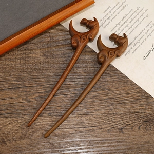 Macro view of carved sandalwood hairpins with dragon motifs on a wooden background