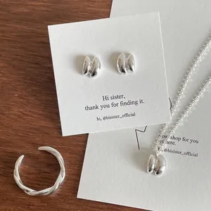 Detailed set of S925 sterling silver key necklace, earrings and spiral ring on wood