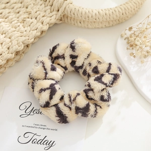 Plush leopard print scrunchie in beige faux fur on a minimalist aesthetic background