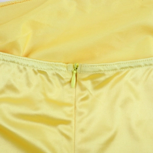 Detail of invisible zipper closure and fine satin fabric texture on yellow dress