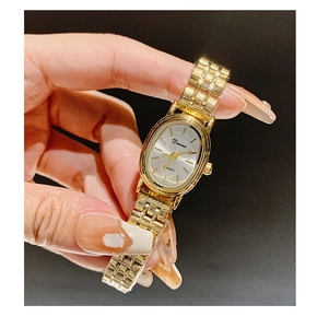 Close-up of elegant gold oval watch with a sleek metal link bracelet on a wrist