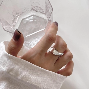 Macro detail of a 925 sterling silver geometric twisted ring on model holding a glass