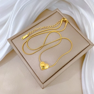 Detail of gold snake chain with heart pendant and lobster clasp on beige jewelry box