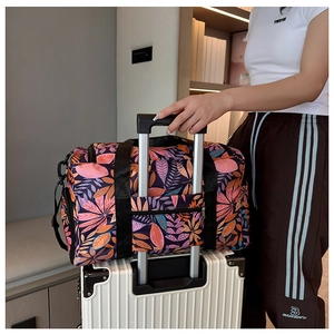 Detail of travel tote bag with leaf print fixed on white luggage handle bar