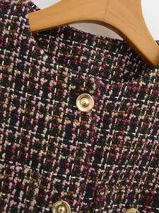 Detail of multi-color tweed texture and gold metal button on a round neck vest