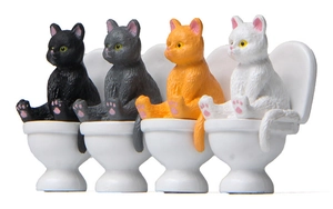 Row of four colorful miniature cats sitting on tiny toilets for creative landscaping