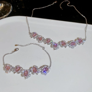 Detailed macro view of pink zircon flower pendant necklace and bracelet set on tray