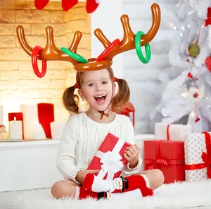 Little girl playing with inflatable reindeer antler ring toss game by the Christmas tree