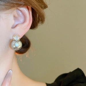 Gros plan d'une boucle d'oreille perle grise avec zircon brillant en style rétro français