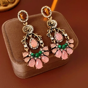 Detailed macro of vintage gold drop earrings with pink and green crystal stones