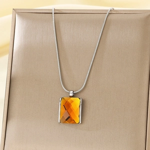 Detail of a rectangle yellow glass pendant with faceted cut on a silver snake chain