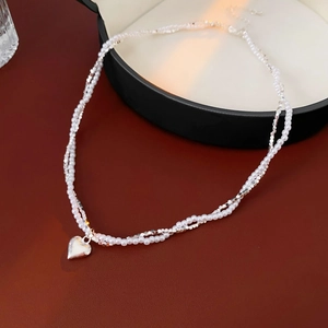 Detail of double-layer necklace with white rice pearls and silver heart pendant