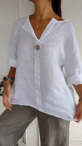 Dettaglio del tessuto in lino bianco e scollo a V con un bottone decorativo in legno