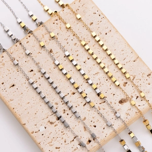 Vintage-style gold and silver tassel necklaces with small cube pendants on stone