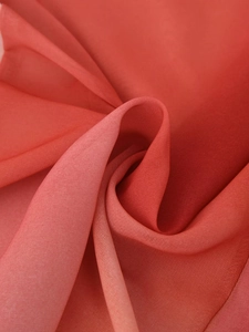 Détail en gros plan montrant la texture douce du mousseline rouge et les plis drapés