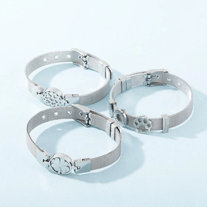 Three-piece silver mesh bracelets with clover and footprint charms on a blue background