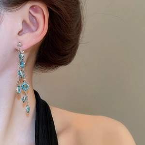 Dettaglio di orecchini pendenti argento con perline azzurre e eleganti nappe lunghe
