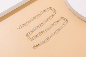 Detail of silver stainless steel paperclip chain necklace on a beige geometric display