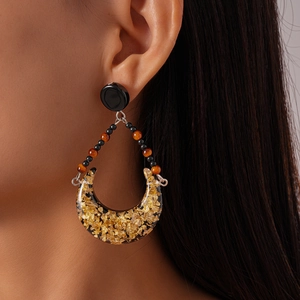Detail of moon-shaped resin earrings with gold foil on a model for bohemian style