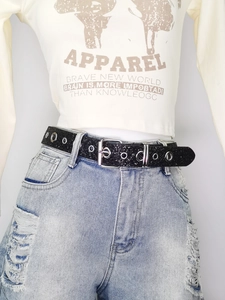 Close-up of black glitter belt with silver metal buckle and double row eyelets on jeans