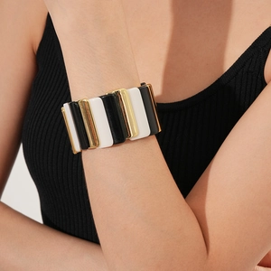 Detail of a geometric stretch bracelet with black, white, and gold enamel block segments