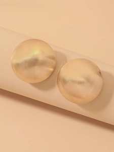 Detailed view of brushed gold spherical geometric stud earrings on a minimalist pedestal