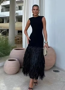 Detailed view of the long black knitted dress featuring elegant fringe hem and open back