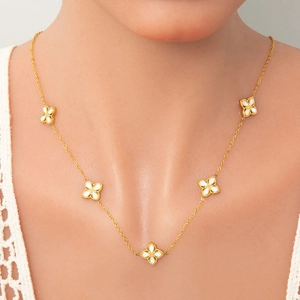 Detail of 18k gold lucky clover necklace with white shell inlay on model's neck