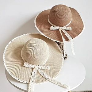 Cappelli di paglia con pizzo e fiocco in marrone e beige su una superficie bianca