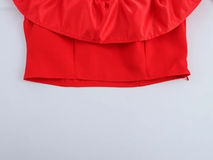 Vue détaillée de l'ourlet du haut rouge avec bords à volants et texture satinée premium