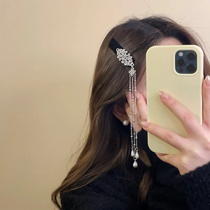 Detailed view of a vintage Chinese style hair clip with silver tassels and pearl droplets