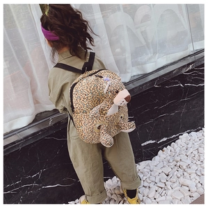 Close-up of a leopard print toddler backpack with a cute plush toy and safety leash