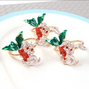 Three silver bunny napkin rings with red carrots and gold bands on a white plate
