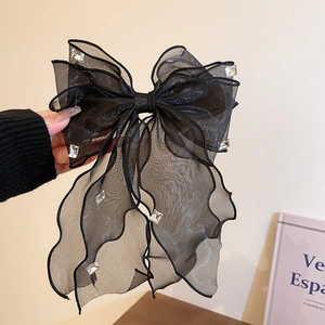 Détail d'une grande pince à cheveux en organza noir ornée de strass blancs étincelants