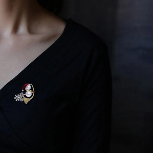 Macro detail of snowman brooch with pearls and snowflakes on black garment