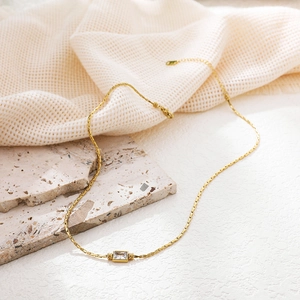 Macro detail of 18K gold-plated snake chain necklace with clear rectangular zircon stone