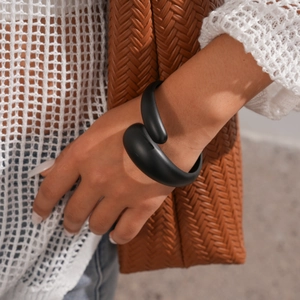 Detail of matte black geometric wrap bracelet on wrist with elegant woven textures