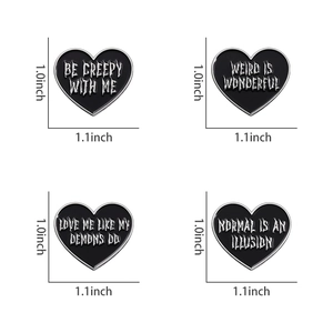 Detailed view of four black gothic heart enamel pins with white artistic lettering