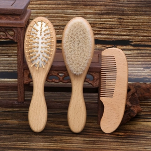 Three-piece wooden baby hairbrush set with soft wool brush and massage comb on wood background