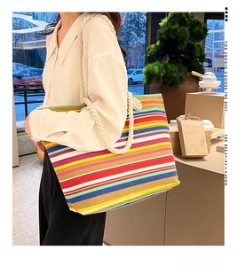 Detail of colorful striped canvas tote bag with thick white rope handles on shoulder