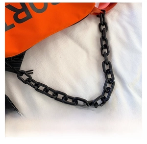 Détail du sac à main orange en nylon avec grosse chaîne noire et imprimé lettré