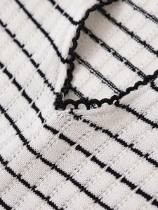 Gros plan sur la maille texturée à rayures noires et bordure festonnée ajourée détaillée