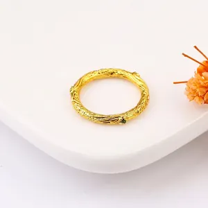 Golden twig texture ring with a tiny green gemstone on a clean white display tray