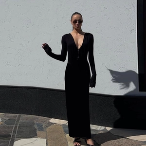 Detail of a chic black long-sleeved dress with a deep V-neck and slimming silhouette