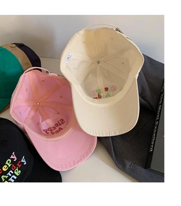 Flat lay of colorful cotton baseball caps with Sleepy Angry embroidery and adjustable strap