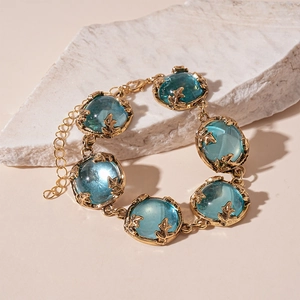 Detailed view of vintage gold leaf bracelet set with large blue round resin stones