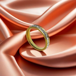 Detailed macro of a gold-plated titanium ring with inlaid cubic zirconia on satin fabric