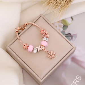 Detail of rose gold charm bracelet with pink glass beads and snowflake pendant on display box